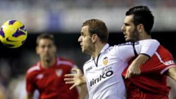 El delantero del Valencia Roberto Soldado protege el bal&oacute;n ante el defensa croata del Sevilla Emir Spahic durante el partido correspondiente a la decimonovena jornada de Liga de Primera Divisi&oacute;n disputado esta tarde en el estadio de Mestalla, en Valencia. 