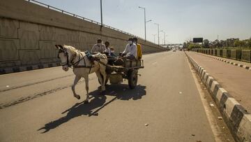 NEW DELHI, INDIA - MARCH 28: Indians travel on a horse drawn vehicle on a deserted road as a nationwide lockdown continues in an attempt to stop the spread of the coronavirus (COVID-19) on March 28, 2020 in New Delhi, India. India is under a 21-day lock
