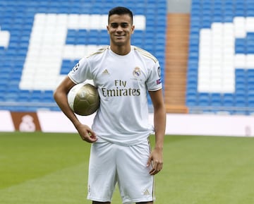 Reinier, vestido de blanco, posa para los medios en el césped del Santiago Bernabéu. 