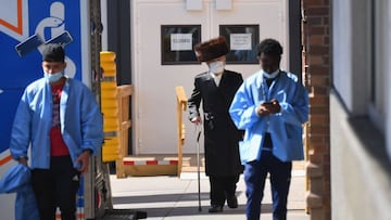 A Hasidic Jewish man(C) wearing a facemask and others walk outside the Maimonides Medical Center in the Brooklyn neighborhood of Borough Park on October 6, 2020 in New York City. - New York will temporarily close schools in nine neighborhoods experiencing