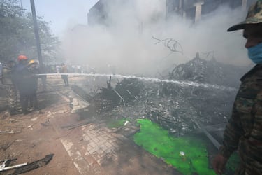 Los bomberos rocían agua en el lugar donde se estrelló un avión en la ciudad de Ahmedabad, en el noroeste de India, en el estado de Gujarat.