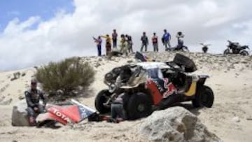Sainz reposa sobre una piedra mientras Cruz bucea en las tripas del Peugeot.
