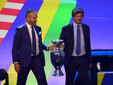 Los ex jugadores Gianluca Zambrotta y Demetrio Albertini de Italia llevan el trofeo antes del sorteo.