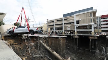 A vehicle teetering on the edge of a massive sinkhole that opened on Samsen Road near Vajira Hospital, is moved to a safe space, in Bangkok, Thailand, September 24, 2025. REUTERS/Chalinee Thirasupa
