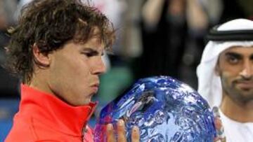 <b>PESADO TROFEO. </b>Nadal levanta el trofeo que le otorgaron por ganar el 'Mubadala World Tennis Championship', en el que repite título.