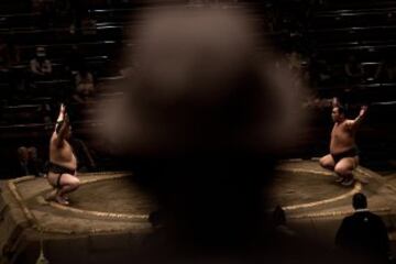 Un hombre presencia uno de los combates entre dos luchadores en el Ryogoku Kokugikan de Tokyo.