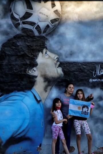 People pose in front of a mural depicting the late soccer legend Diego Armando Maradona near Bella Vista cemetery, where Maradona is buried, on the outskirts of Buenos Aires