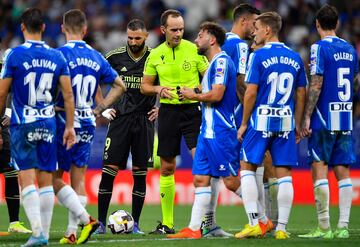 Spanish referee Mario Melero Lopez (C) talks with Espanyol's players as Real Madrid's French forward Karim Benzema (3L) prepares to shoot a free kick during the Spanish League football match between RCD Espanyol and Real Madrid CF at�the RCDE Stadium in Cornella de Llobregat on August 28, 2022. (Photo by Pau BARRENA / AFP)