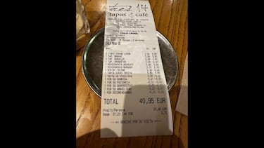 Un cliente de un bar de M¨¢laga, perplejo tras leer el ticket de la cuenta: descuentos por amabilidad, sonrisa...