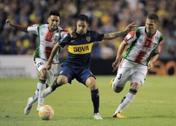 Juan Manuel Martinez(c) de Boca Juniors disputa la pelota con German Lanaro y Diego Torres de Palestino.