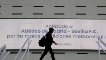 Un aficionado pasa ante el cartel del Metropolitano anunciando la suspensión del Atlético-Sevilla por unas condiciones metereológicas avisadas por la AEMET que nunca se produjeron.