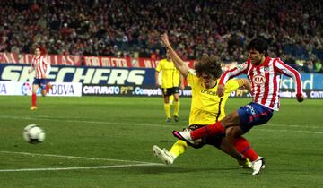 El jugador del Atl¨¦tico Ag¨¹ero remata a puerta ante el jugador del Barcelona Puyol.