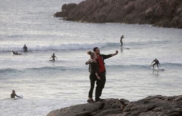 Dos jóvenes se hacen una foto este sábado en la playa del Orzán de A Coruña, en una jornada en la que cientos de personas se han agolpado en los arenales y paseo marítimo de la ciudad, en el que ha sido el primer día que las personas adultas salen a la calle a pasear y hacer deporte individual en franjas horarias distintas. 