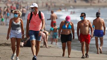 Several people walk along the beach wearing face masks, as the regional government of the Canary Islands forbids smoking without maintaining a safe distance and imposes a mandatory rule to wear protective masks in open public spaces, amid the coronavirus 
