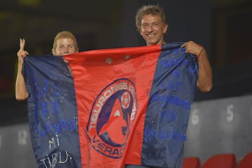 Un par de aficionados sostienen una bandera de los Tiburones Rojos del Veracruz.