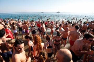 Decenas de ciudadanos participaron este mediodía en el tradicional primer baño del año en la playa de Sant Sebastià del barcelonés barrio de la Barceloneta.