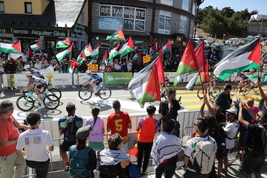 Varios ciclistas pasan por una zona con protestas propalestinas durante la 20ª etapa de la Vuelta Ciclista a España.