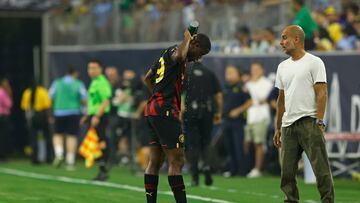 Manchester City FC defender Luke Mbete (L) sprays himself down with a gatorade bottle as he talks with manager Pep Guardiola during their pre season friendly football match between Manchester City FC and Club America on July 20, 2022 at NRG Stadium in Houston, Texas. (Photo by AARON M. SPRECHER / AFP)