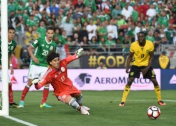 Guillermo Ochoa se lanza para atajar el balón.