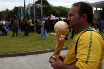 Un hombre sostiene la réplica de la Copa Mundial de la FIFA mientras maestros de Río de Janeiro protestan frente al hotel donde se alojan los jugadores de la selección brasileña de fútbol.