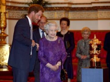 El príncipe Harry y la reina Isabel II observan la Copa Webb Ellis, que recibirá el campeón de la Copa del Mundo de Rugby.