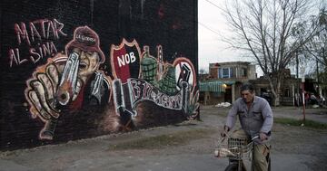 Un hombre pasea en biclieta al lado de un mural de ultras del Newell´s Old Boys.