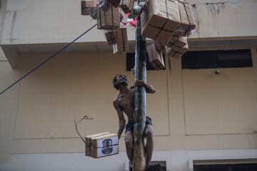 Un hombre trepa por un poste para coger uno de los regalos colgados en él.