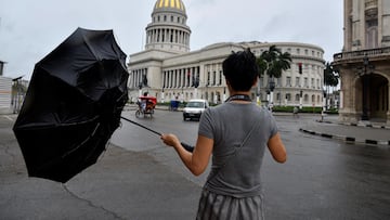 A tourist from China tries to hold his umbrella as Hurricane Rafael passes by Havana, Cuba, November 6, 2024. REUTERS/Norlys Perez
