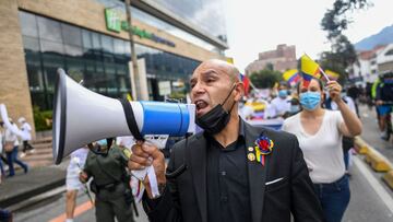 A man using a megaphone shouts slogans during a demonstration in opposition to road blockades and violence, after a month of national protests, in Bogota, on May 30, 2021. - Large groups of protesters dressed in white are mobilizing this Sunday, May 30, against protests and road closures in Colombia that unleashed a severe crisis that leaves almost 60 dead in clashes between police and armed civilians. (Photo by Juan BARRETO / AFP)