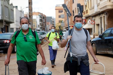 La gente lleva cubos y escobas, tras las fuertes lluvias que provocaron inundaciones, en Sedaví. 