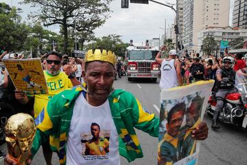 Los seguidores de la difunta estrella del fútbol brasileño Pelé abarrotan la calle mientras un camión de bomberos transporta el ataúd de Pelé al Cementerio Conmemorativo de Santos en Santos.
