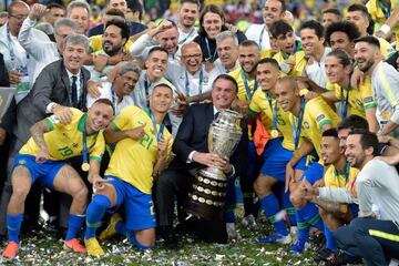 July 07, 2019: Brazilian President Jair Bolsonaro holds the Copa America trophy as members of the Brazilian national team celebrates after winning the title by defeating Peru in Rio de Janeiro, Brazil.