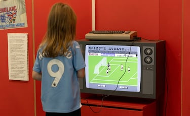 Un niño, con la camiseta de Haaland, disfruta con un videojuego de los años ochenta.