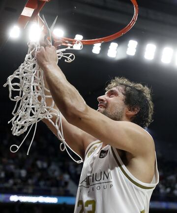 El jugador del Real Madrid, Sergio Llull, corta con unas tijeras la red de la canasta. 