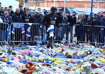Darnell Johnson places a shirt among the wreaths of flowers and messages of condolence for Vichai Srivaddhanaprabha and the other four people killed in a helicopter accident.