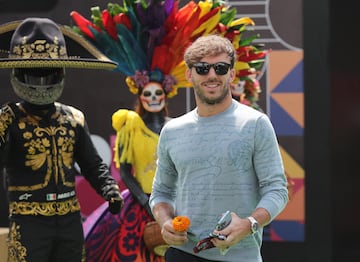 Pierre Gasly recibe una flor de cempasúchil de manos de una persona vestida de catrina antes del Gran Premio de México.