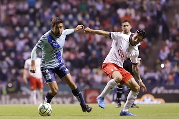 El jugador Pablo González de Puebla disputa el balón con Carlos Cisneros de Guadalajara hoy, durante un partido de la jornada11 del torneo Clausura 2023 de la liga del fútbol mexicano en el estadio Cuauhtémoc, en Puebla.
