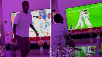 Vinicius casually games in a living room flooded with trophies