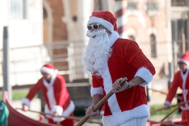 Personas vestidas de Papá Noel reman durantela  regata navideña en el Gran Canal de Venecia.