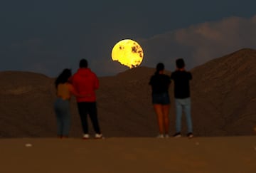 La gente observa la salida de la luna llena antes del eclipse lunar en las Dunas de Samalayuca, en las afueras de Ciudad Juárez, México.