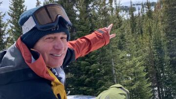 Jake Burton Carpenter, fundador de Burton Snowboards, señalando una montaña que queda tras unos árboles.