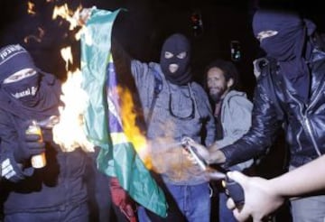 Manifestantes queman una bandera brasileña durante una protesta en contra de la Copa del Mundo de 2014 en Sao Paulo.