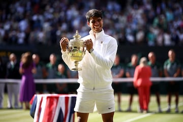Carlos Alcaraz posa con el trofeo de campeón de Wimbledon en el césped de la pista central.
