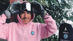 El snowboarder Kevin Pino, guantes y sudadera puesta, con la tabla de snowboard al lado, poni&eacute;ndose la m&aacute;scara de nieve. En Andorra.