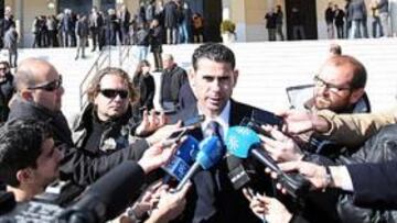 <b>MOMENTO MUY DURO. </b>Fernando Hierro atiende a los medios mientras de fondo multitud de personas aguardan en la puerta de la capilla tras la misa.