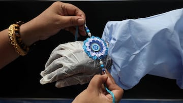 A woman ties a Rakhi, traditional Indian sacred thread, on the wrist of a municipal worker wearing personal protective equipment (PPE) to celebrate the Hindu festival of Raksha Bandha, during which a sister ties one or more of the sacred threads onto her