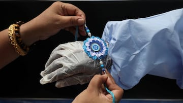 A woman ties a Rakhi, traditional Indian sacred thread, on the wrist of a municipal worker wearing personal protective equipment (PPE) to celebrate the Hindu festival of Raksha Bandha, during which a sister ties one or more of the sacred threads onto her 