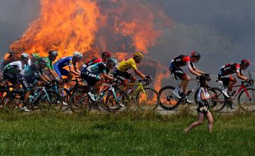 El pelotón, con Greg Van Avermaet con el maillot amarillo pasa cerca de unas pacas de paja de heno.