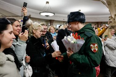 Un militar entrega flores a mujeres durante un concierto de una orquesta militar celebrado en una estación de metro para celebrar el Día Internacional de la Mujer en Moscú.