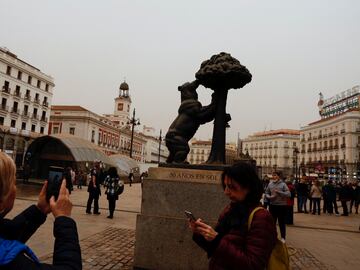 Turistas visitando la plaza de la Puerta del Sol bajo el polvo sahariano traído por la tormenta Celia.